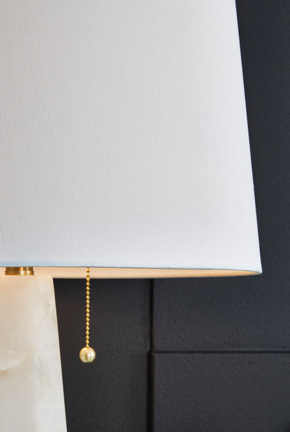 White fabric lamp shade with gold pull chains on alabaster base