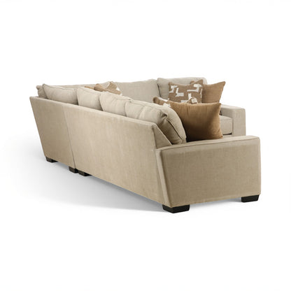 Beige sectional sofa with wide chaise end, tufted cushions, and decorative pillows