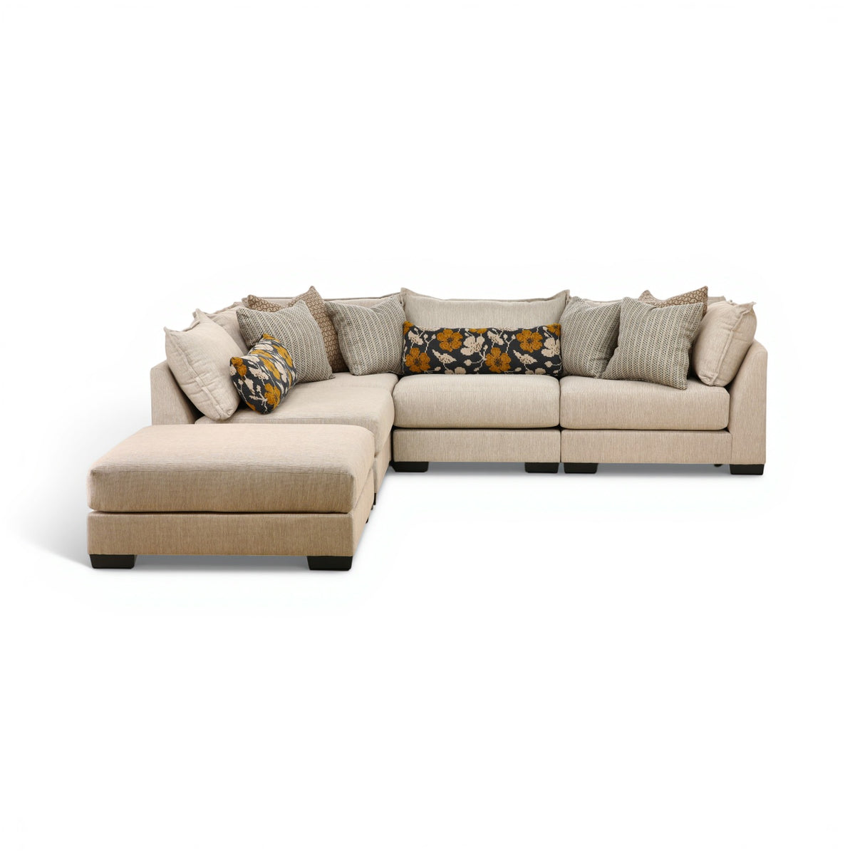 Beige modular sectional sofa with chaise, cushioned ottoman, and patterned throw pillows