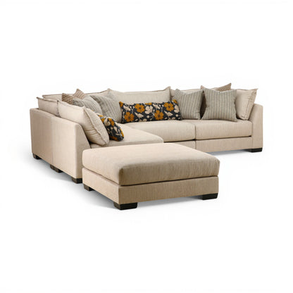 Beige modular sectional sofa with chaise, tufted cushions, and patterned accent pillows