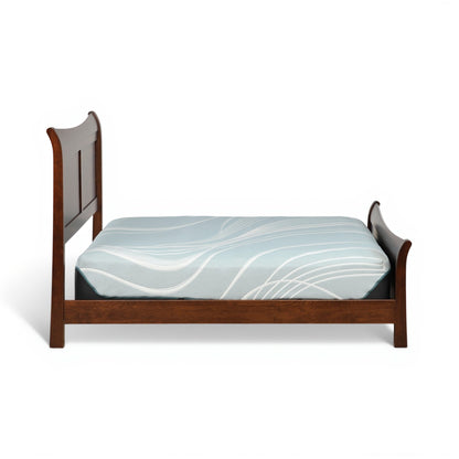 Brown sleigh bed with curved headboard and blue patterned bedding