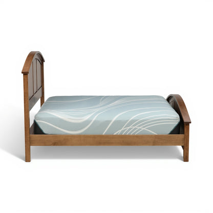 Wood bed with arched end panels and light-blue patterned mattress cover