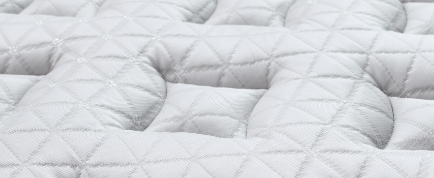 Close-up of a quilted white mattress pad with a textured surface.