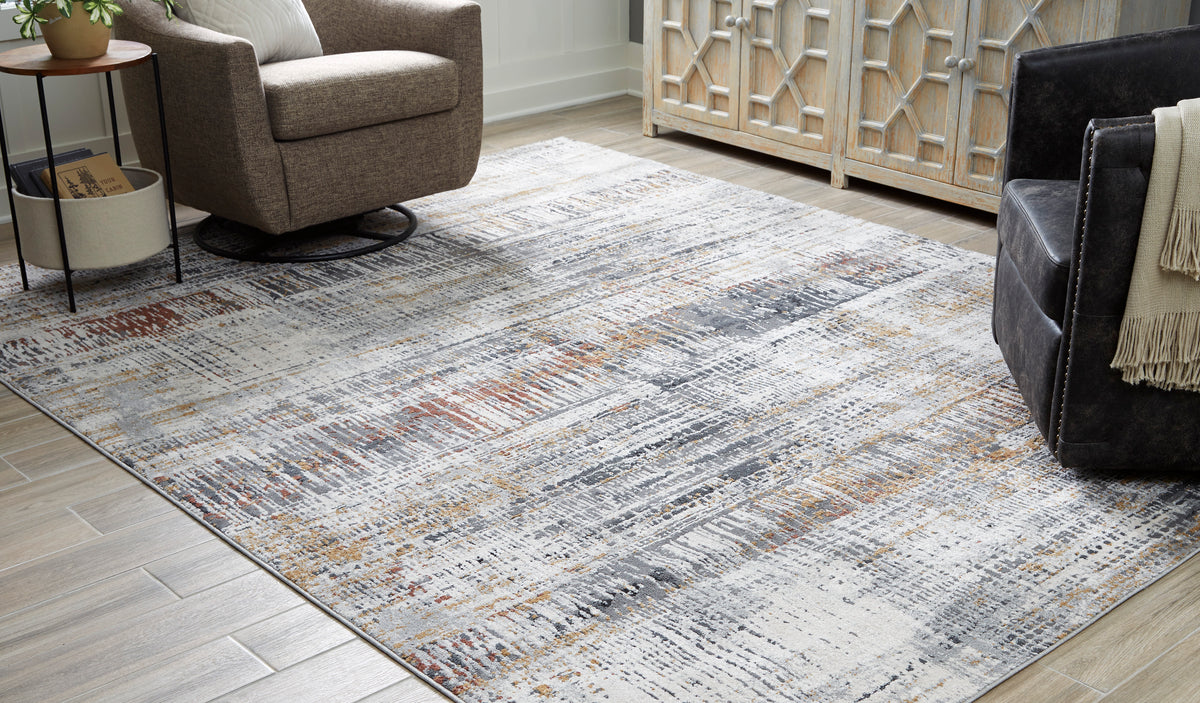 Area rug in light gray with distressed abstract pattern and orange and dark flecks