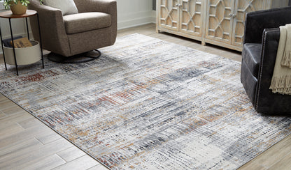 Area rug in light gray with distressed abstract pattern and orange and dark flecks