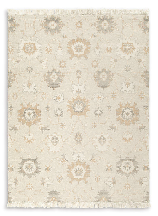 Cream area rug with repeating floral and geometric motifs in light gray and tan fringe