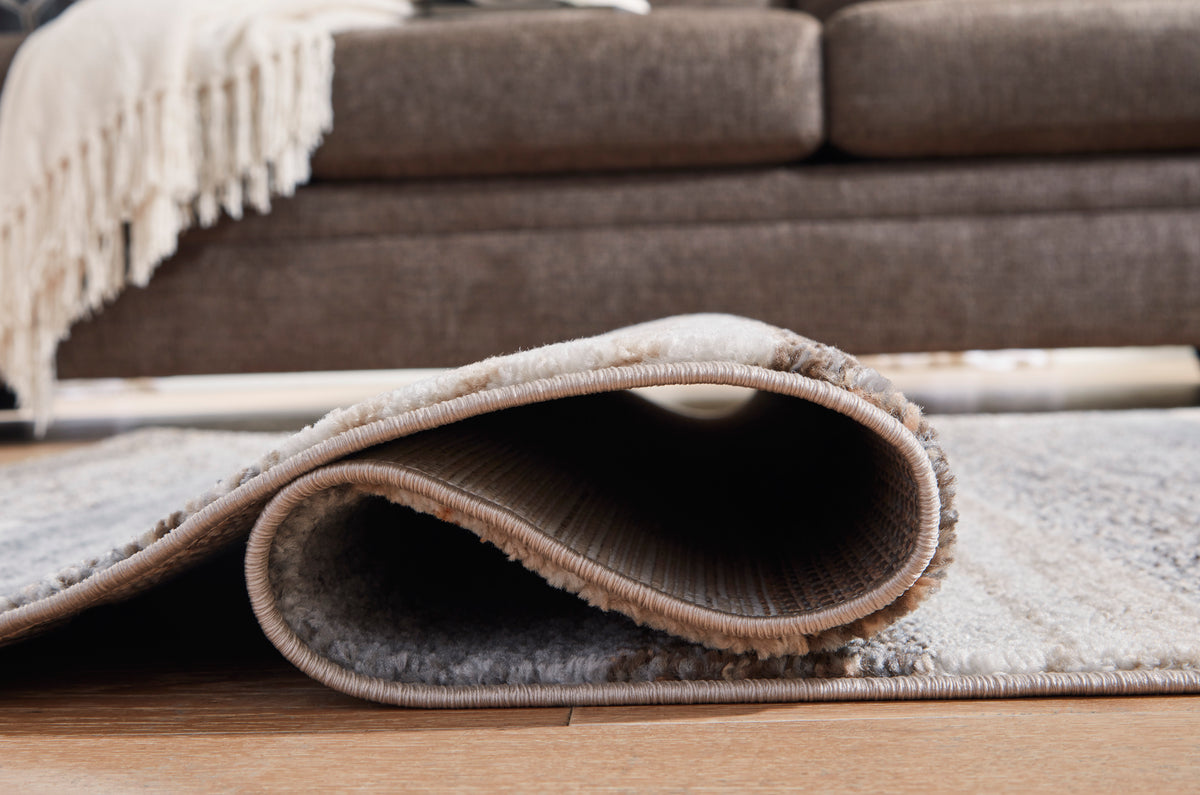 Ashley Sethburn rug corner close-up with stitched border and layered abstract pattern