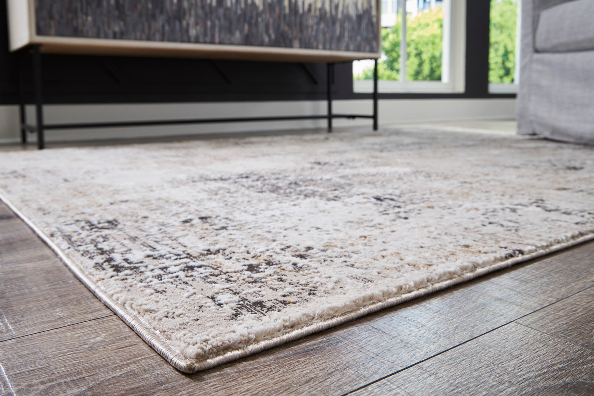 Light beige distressed area rug with gray speckled design and stitched border
