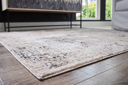 Light beige distressed area rug with gray speckled design and stitched border