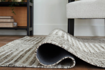 Geometric area rug with textured pile and woven border, rolled corner showing underside.
