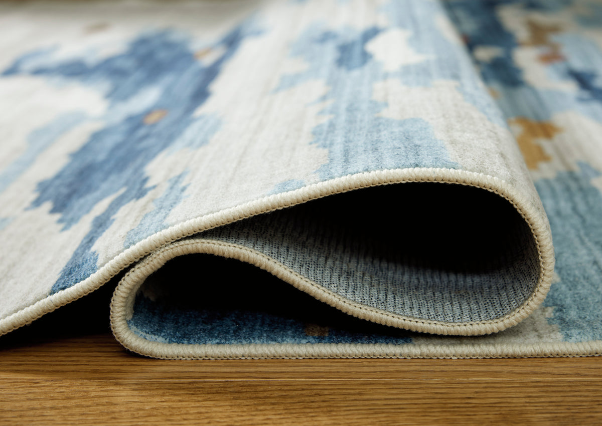 Blue and white abstract rug with stitched border, close-up pile edge