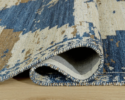 Corner detail of geometric area rug with blue-and-beige pattern and stitched edge.
