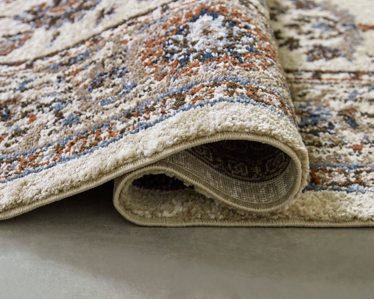 Medium rug close-up: textured pile with beige loop edge and multicolor pattern