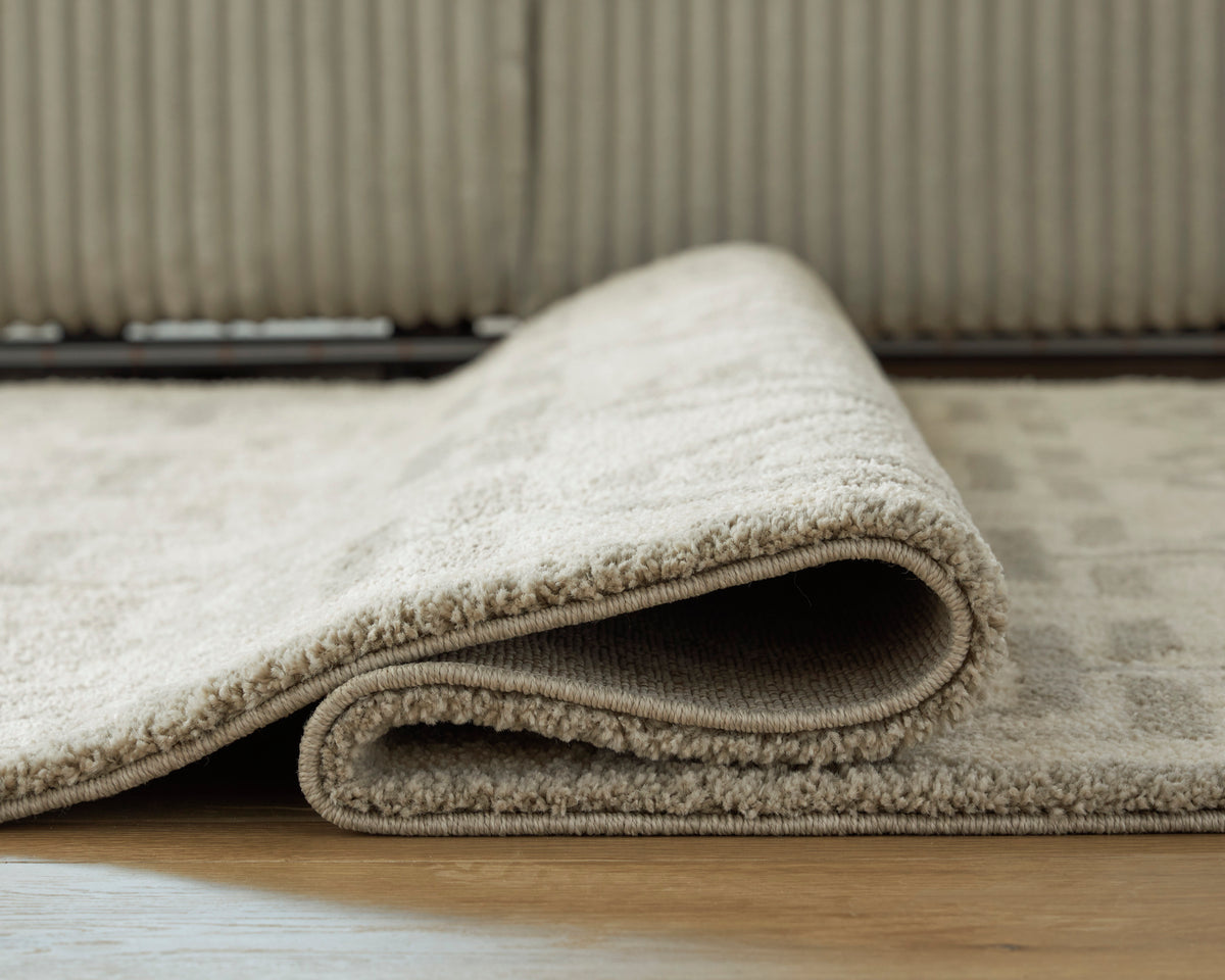 Ashley Maconville rug edge close-up, plush pile with dark gray border