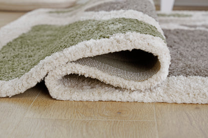 Ashley Anburgh rug showing plush low-pile texture and curled edge; green and gray