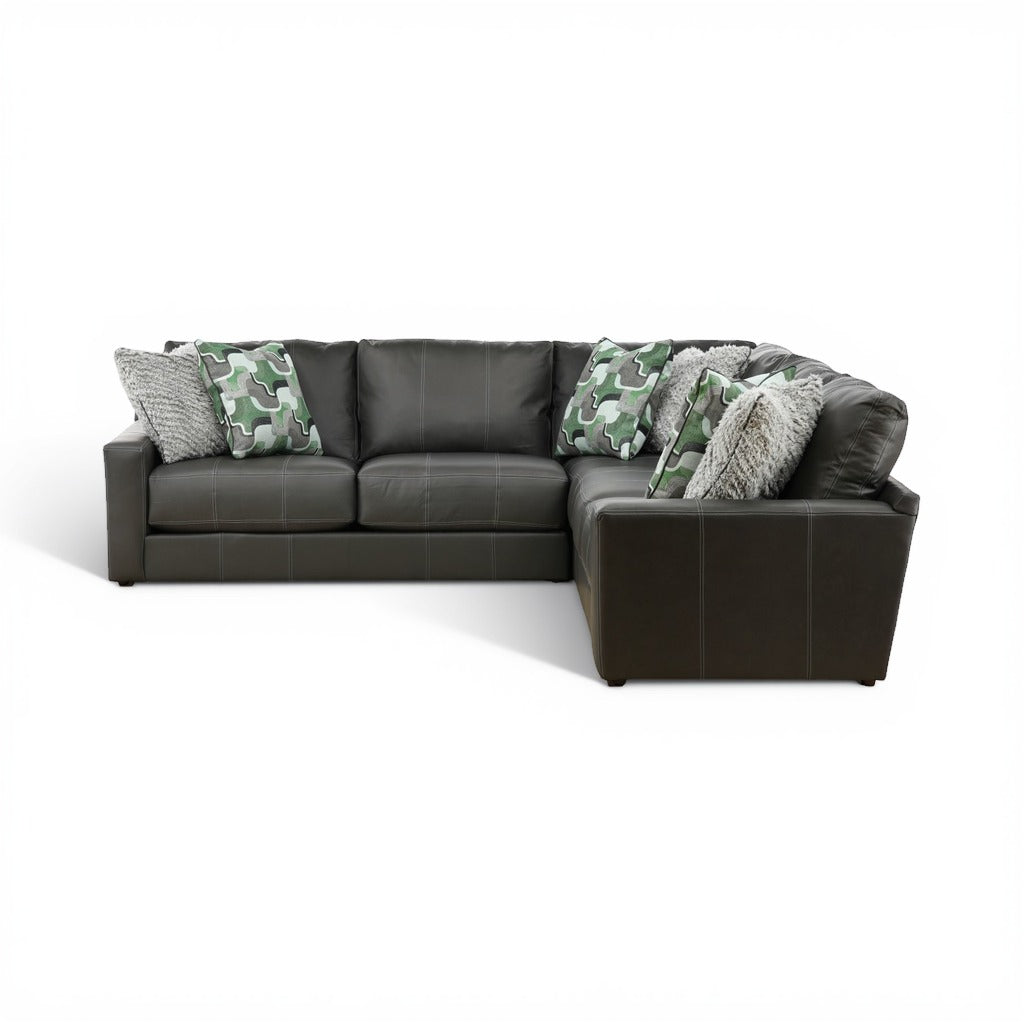 Dark gray sectional sofa with green camo pillows and chunky gray throw on chaise