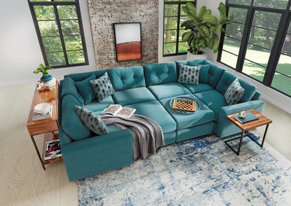 Teal modular sectional sofa with patterned pillows, draped blanket, and corner chaise