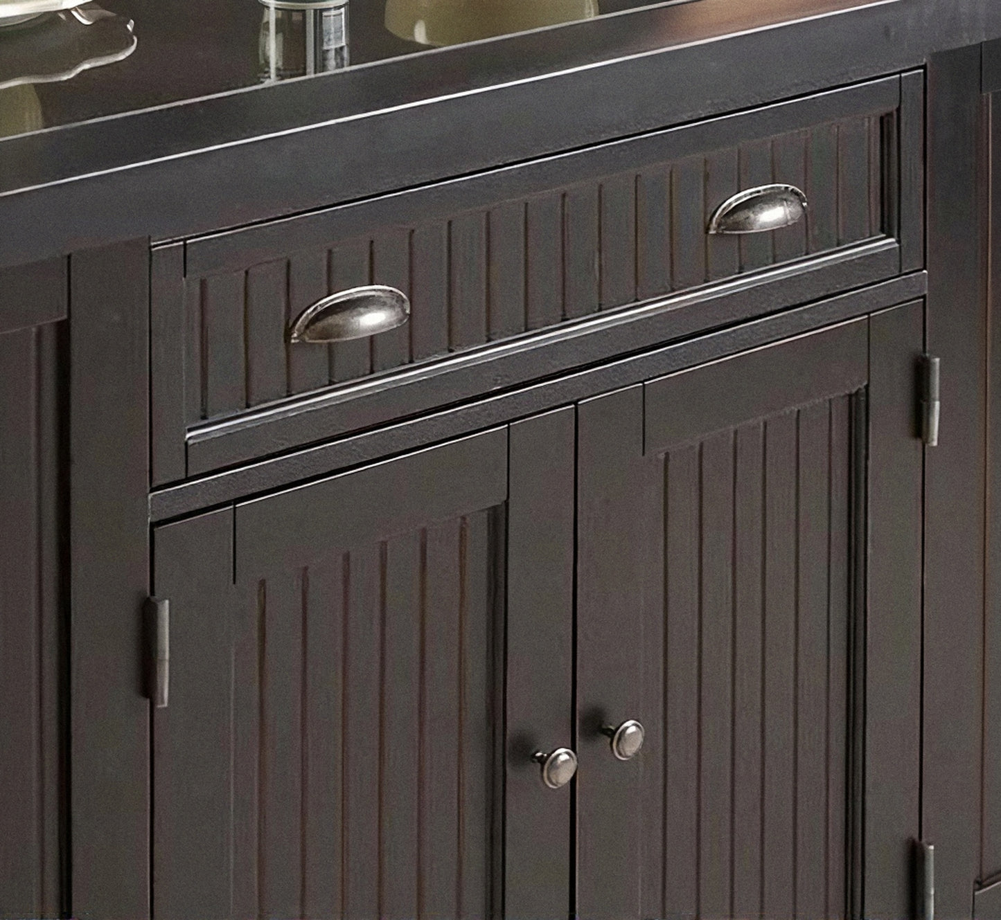 Dark kitchen island cabinet with paneled doors, drawers, and silver metal handles