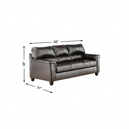 Dark leather sofa with tufted back, armrests, and short legs, 88 in wide.