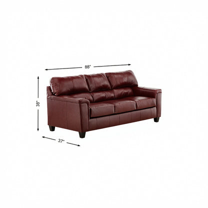 Crimson leather sofa with tufted back cushions, armrests, and short legs, 86 in wide.